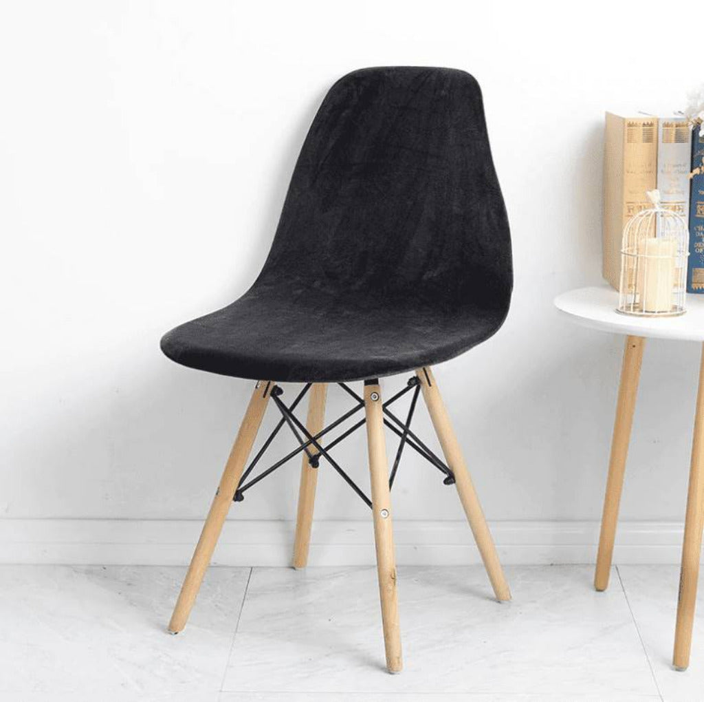 Housse en velours noir pour chaise scandinave, extensible et confortable, pieds bois clair.